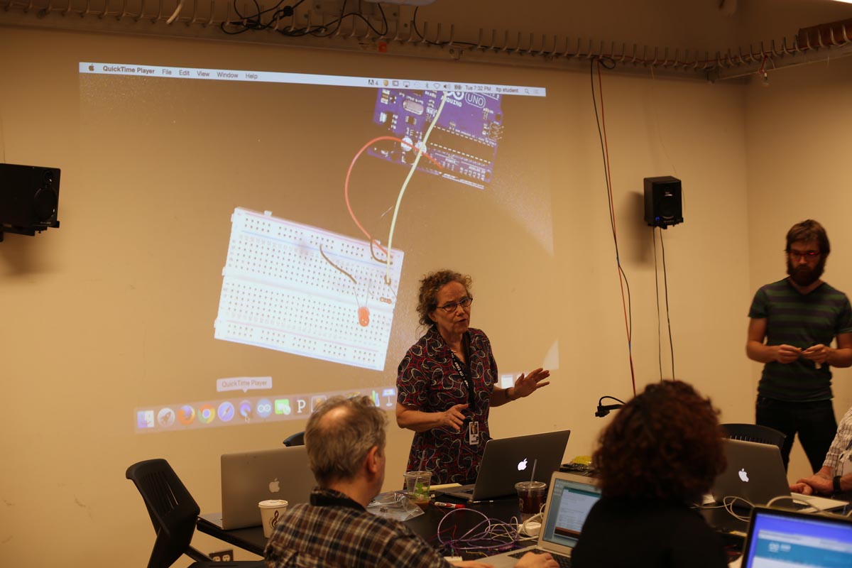 a woman giving a lecture about the Arduino and breadboard